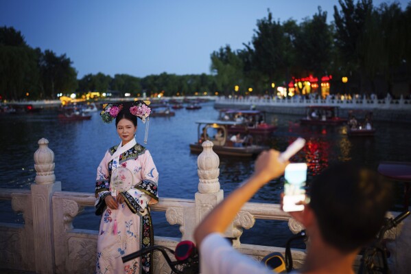 A Chinese girl dressed in Qing Dynasty attire stands for photographs at Shichahai lake in Beijing, China, Tuesday, July 16, 2024. (AP Photo/Vincent Thian)