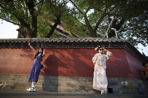 A Chinese girl dressed in Qing Dynasty costume poses for a photograph outside Drum Tower at Gulou East Street in Beijing, China, Wednesday, July 3, 2024. (AP Photo/Vincent Thian)