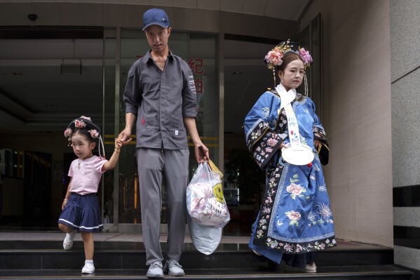 Chinese walk out of a building that provides a one stop solution for achieving the Qing Dynasty traditional look in Beijing, China, Sunday, July 21, 2024. (AP Photo/Vincent Thian)