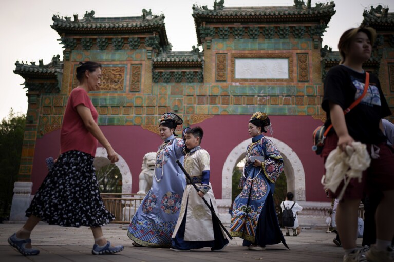 Chinese dressed in Qing Dynasty attire walk at Beihai park in Beijing, China, Sunday, July 28, 2024. (AP Photo/Vincent Thian)