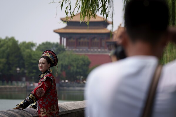 A Chinese woman dressed in Qing Dynasty attire takes pictures near the Forbidden city in Beijing, China, Sunday, July 21, 2024. (AP Photo/Vincent Thian)