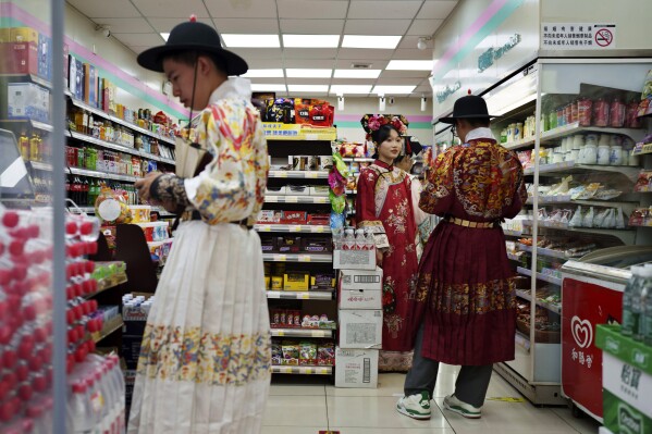 A group of students from the elite Tsinghua University, who celebrated their end of semester dressed in Qing Dynasty attire, shop at a convenience store in Beijing, China, Sunday, July 21, 2024. (AP Photo/Vincent Thian)