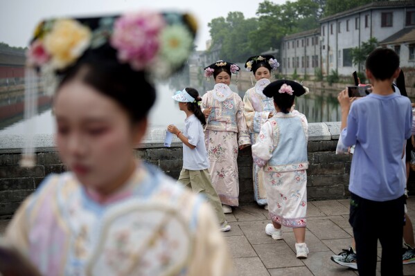 Chinese dressed in Qing Dynasty attire take pictures near the side entrance of Forbidden city in Beijing, China, Monday, July 22, 2024. (AP Photo/Vincent Thian)