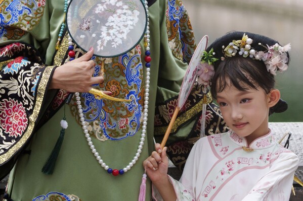 A Chinese girl dressed in Qing Dynasty attire stands for photographs near the Forbidden city in Beijing, China, Sunday, July 21, 2024. (AP Photo/Vincent Thian)