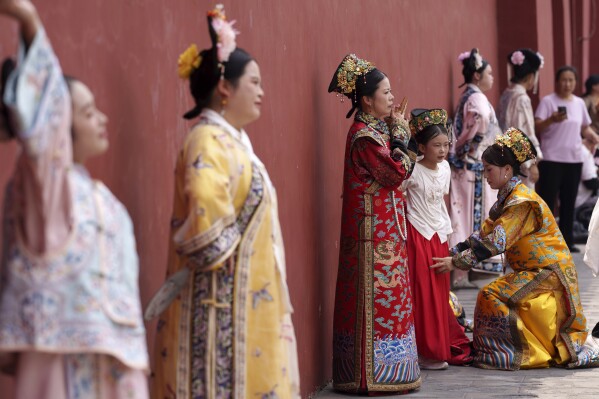 Chinese women dressed in Qing Dynasty attire stands for photographs near the Forbidden city in Beijing, China, Sunday, July 21, 2024. (AP Photo/Vincent Thian)