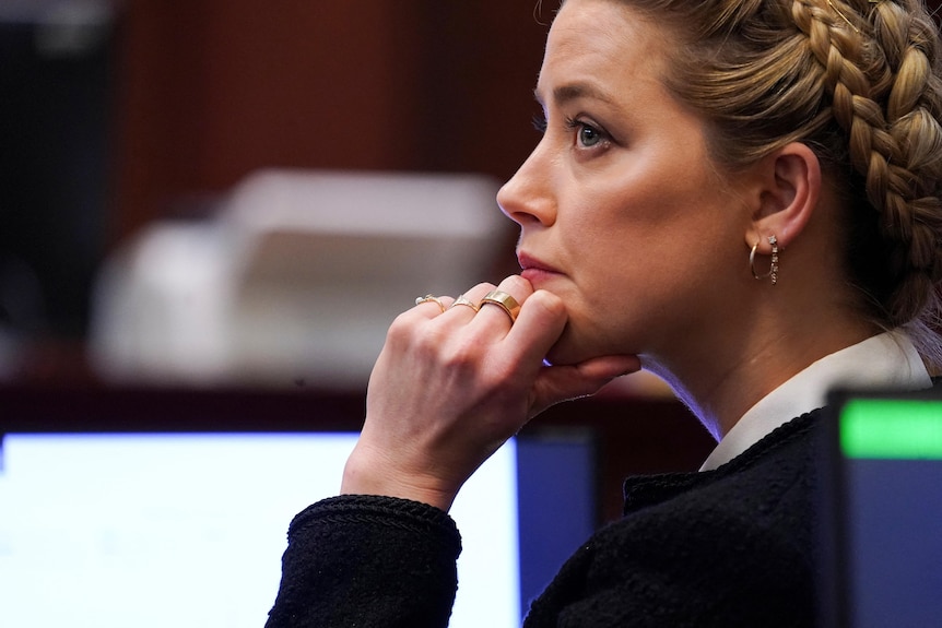 side view of Amber Heard in which she has her hand to her chin and hair braided and pulled back