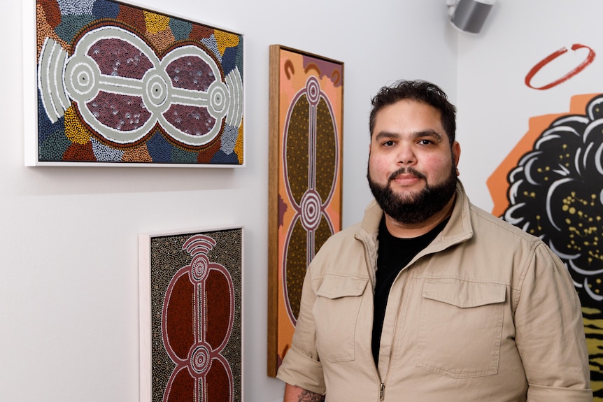 Emrhan Sultan in front of Indigenous dot paintings