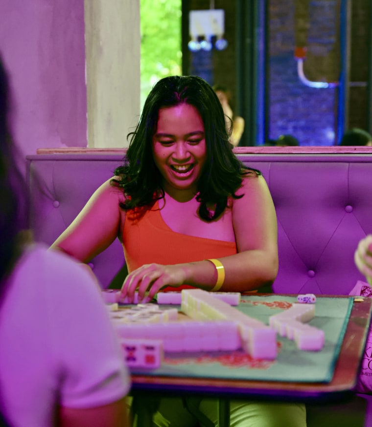 Akiko Barreras shows her winning hand of mahjong to the other players under the purple lights of Hana House.