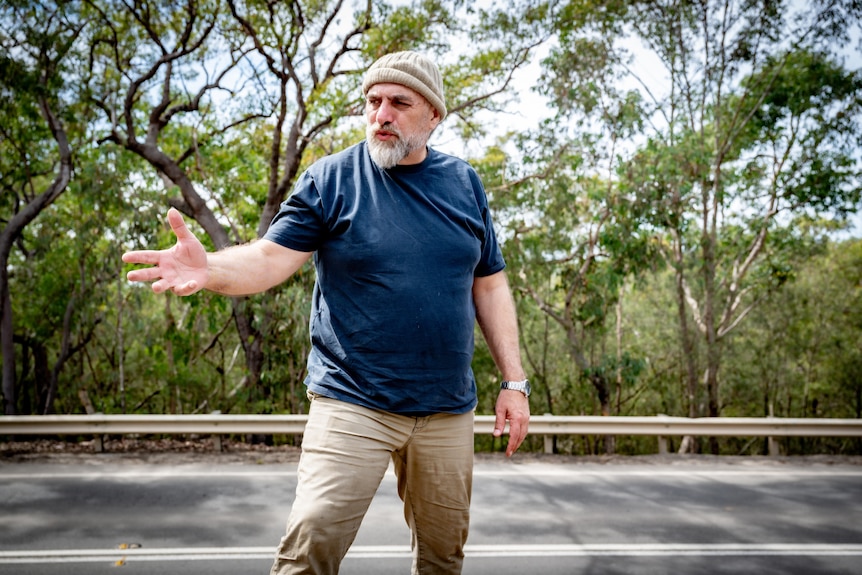 Shane Smithers stands on the roadside, gesturing with his hand