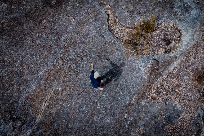 Aerial shot showing Shane Smithers standing barefoot on a large flat rock surface