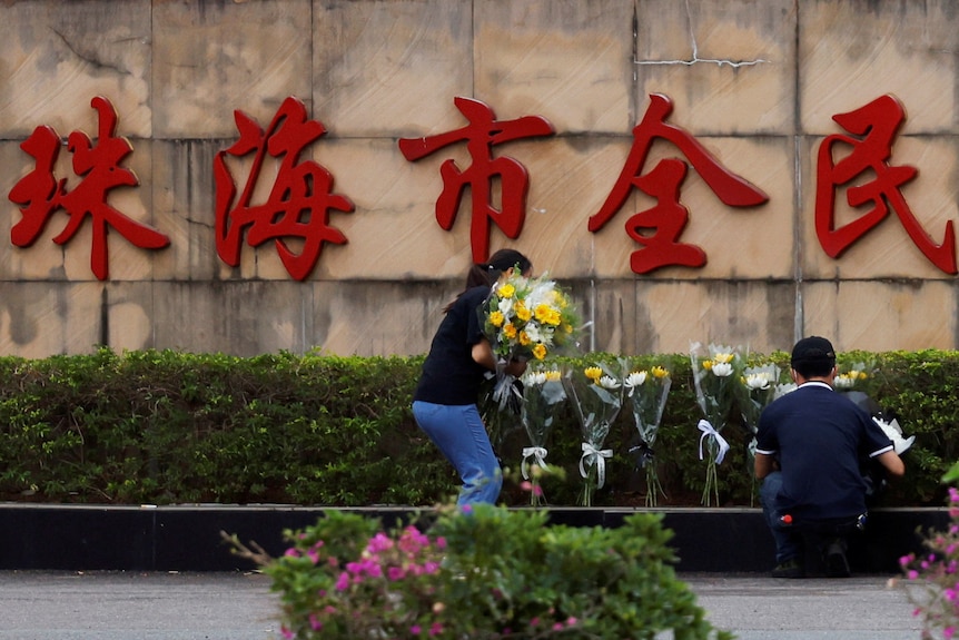 People remove flower bouquets placed outside the sports centre where the deadly attack took place