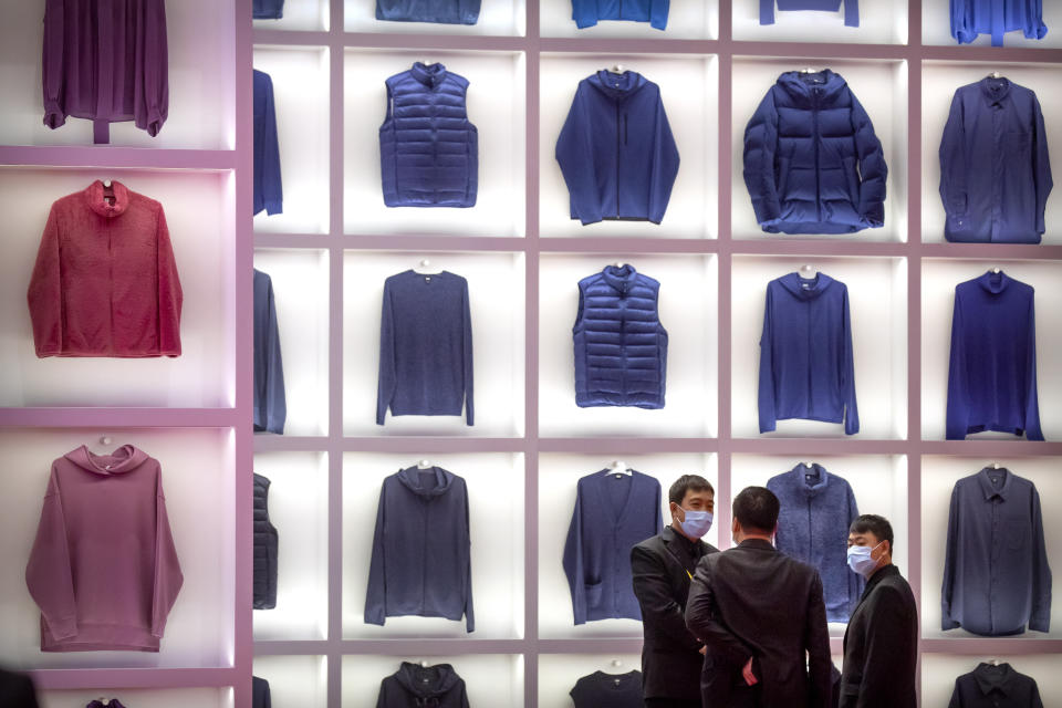 Visitors wearing face masks to protect against the coronavirus stand in front a display from clothing retailer Uniqlo at the China International Import Expo in Shanghai, Thursday, Nov. 5, 2020. Chinese leaders are conducting an import fair under intensive anti-coronavirus controls in their latest effort to revive the world's No. 2 economy while the United States and Europe struggle with a renewed surge of infections. (AP Photo/Mark Schiefelbein)