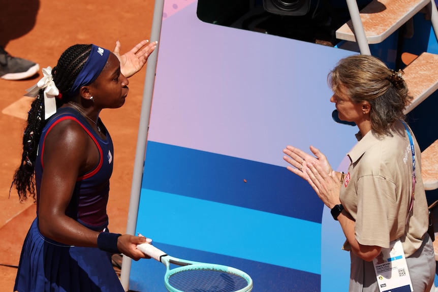 A female tennis player disputes a call with the umpire 