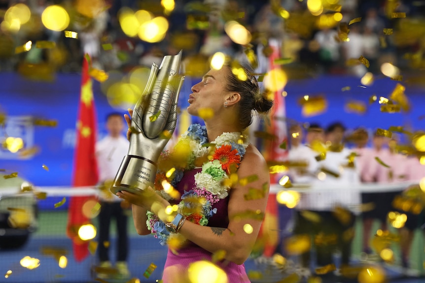 Woman kissing trophy as gold confetti falls.