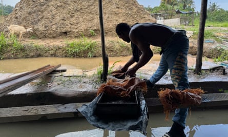 Man sifting deposits beside a dug-up pile of earth