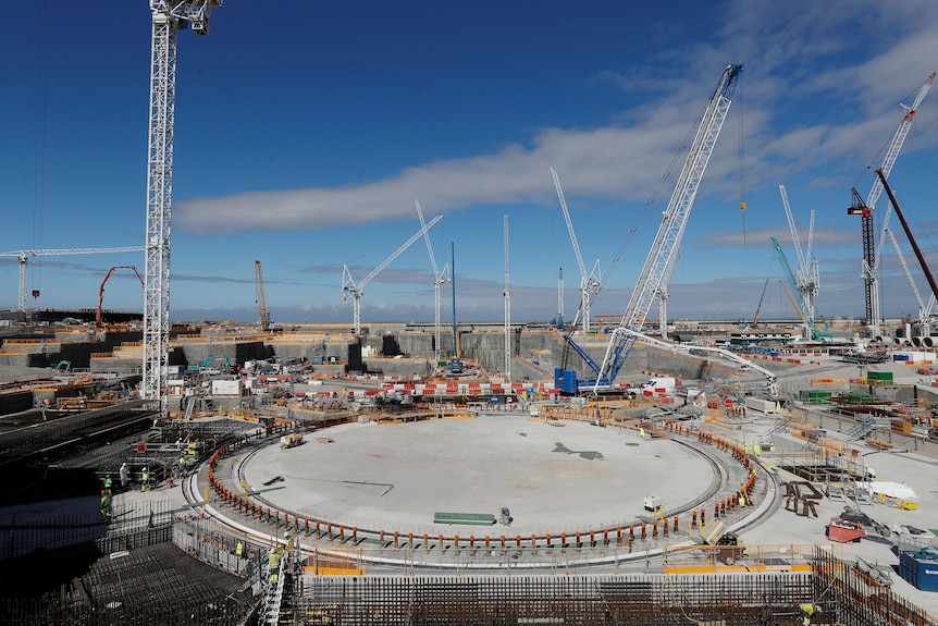 Nuclear power plant under construction with huge concrete footings and cranes everywhere