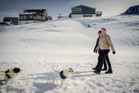 Frederiksen and Egede walk near sled-dogs in a snowy landscape with houses in the background