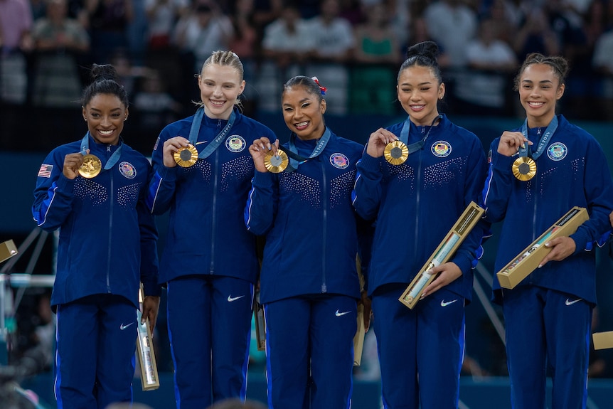 Simone Biles and the US team poses with gold medals