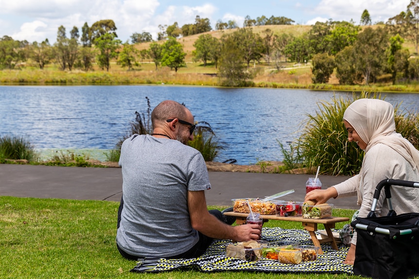 Lina Jebeile on a picnic with her husband, sharing food with water in the background. Relaxing together on the weekend.  