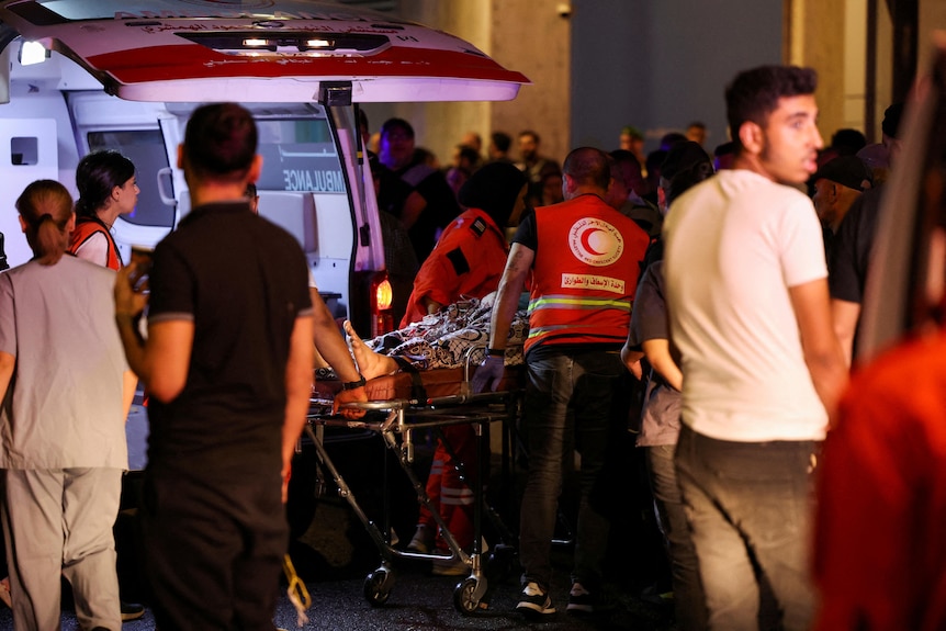 A group of people mill around an ambulance 