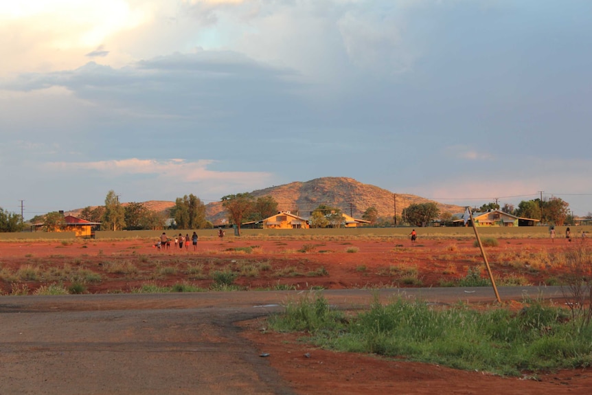 A desert landscape with small figures walking away.