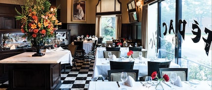 interior of restaurant with white linens on tables and white and black checkered floor tiles