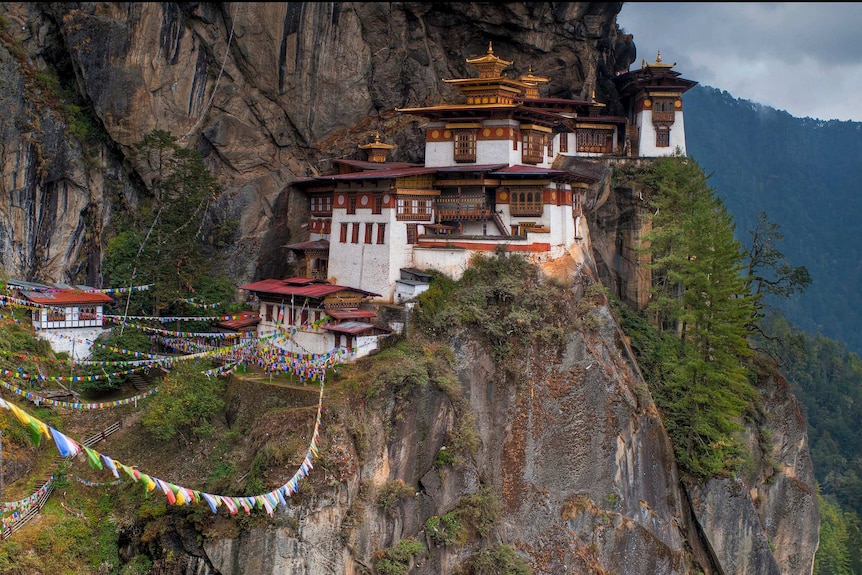 A Buddhist temple on a mountainside along with prayer flags.