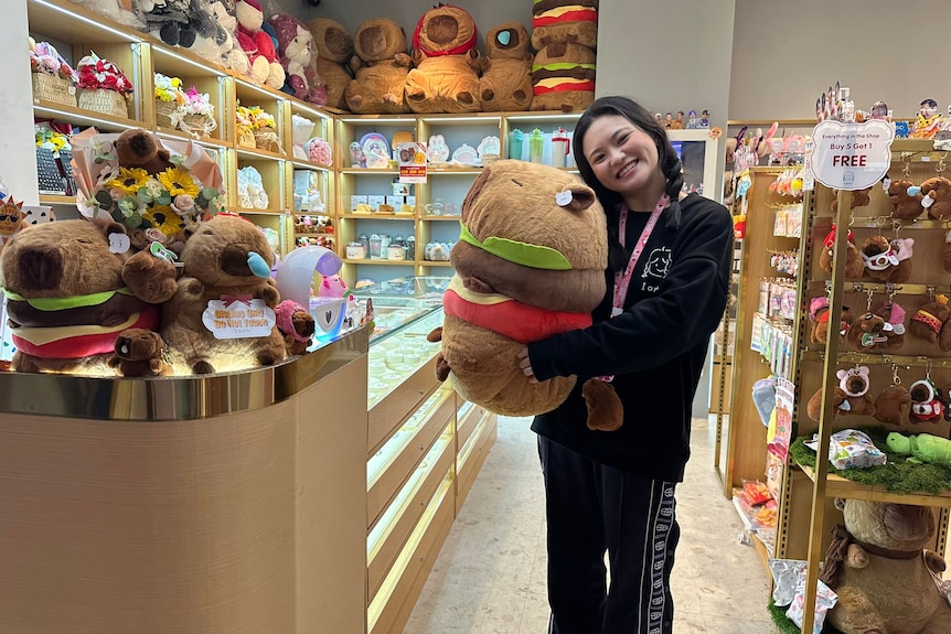 A girl holding a capybara soft toy.