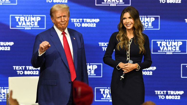 Republican presidential nominee former U.S. President Donald Trump gestures next to South Dakota Governor Kristi Noem during a town hall campaign event in Oaks, Pennsylvania, U.S., October 14, 2024. REUTERS/David Muse