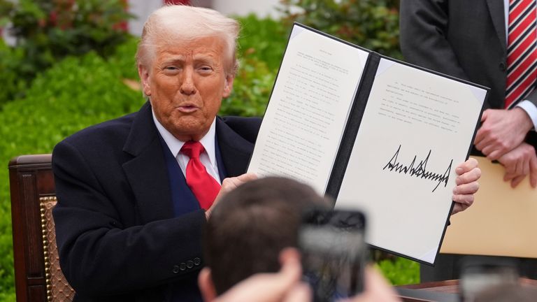 President Donald Trump holds a signed executive order during an event to announce new tariffs in the Rose Garden of the White House, Wednesday, April 2, 2025, in Washington. (AP Photo/Evan Vucci)