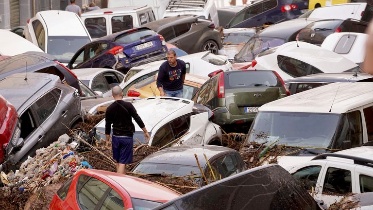 Residents look at cars piled up after being swept away by floods in Valencia, Spain, Wednesday, Oct. 30, 2024. (AP Photo/Alberto Saiz)